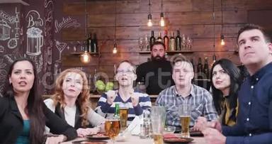 一群朋友正在老式酒吧或餐馆里看电视上的体育比赛